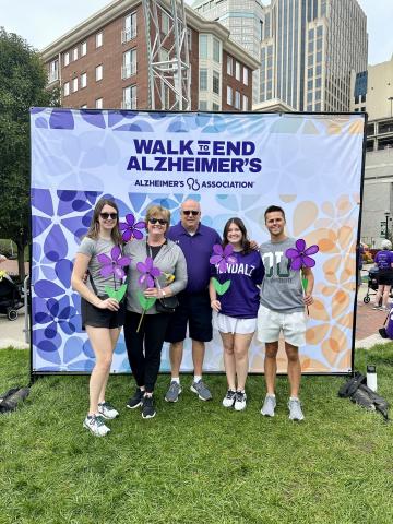 Clara and her family in front of a Walk to End Alzheimer's banner